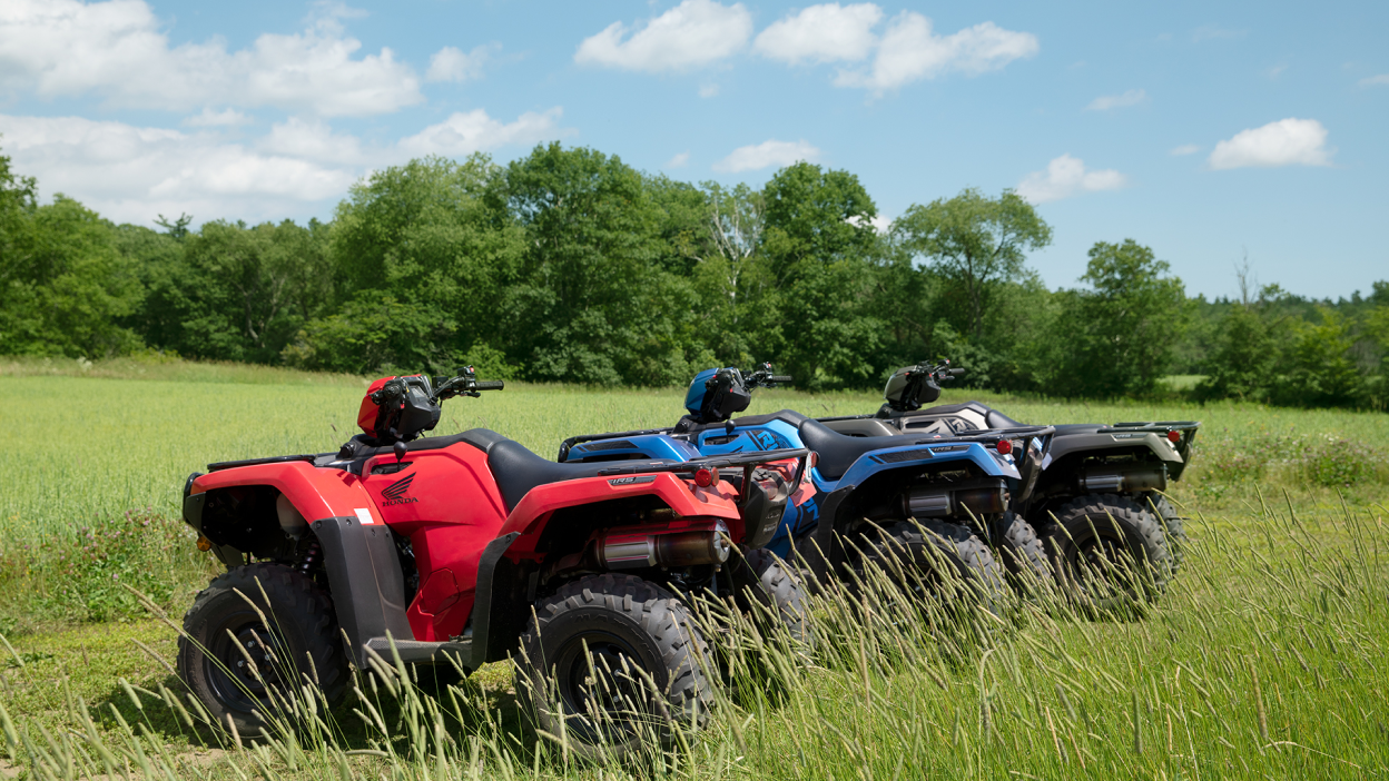 Three Honda Rubicons parked in high grass 