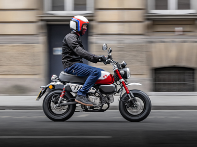 Un cavalier sur un singe Honda en milieu urbain