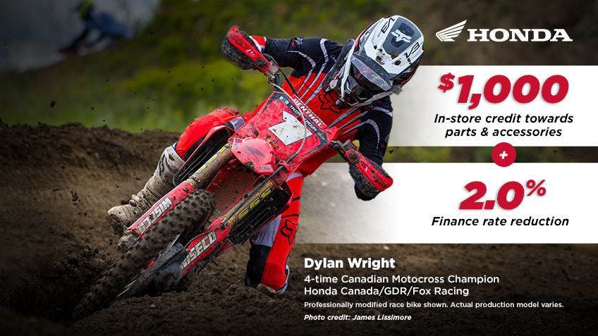 A Honda racer on his bike on a track, raising his arms in victory. Photo credit to James Lissimore.