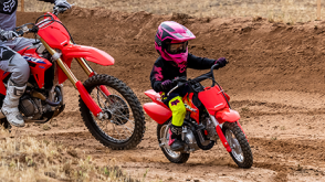 A rider on a Honda Trail motorcycle on a dirt track