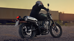 A rider on a Honda SCL500 beside a train