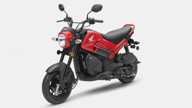 A 3/4 view of a Honda Navi and rider showing its  seat and foot pegs