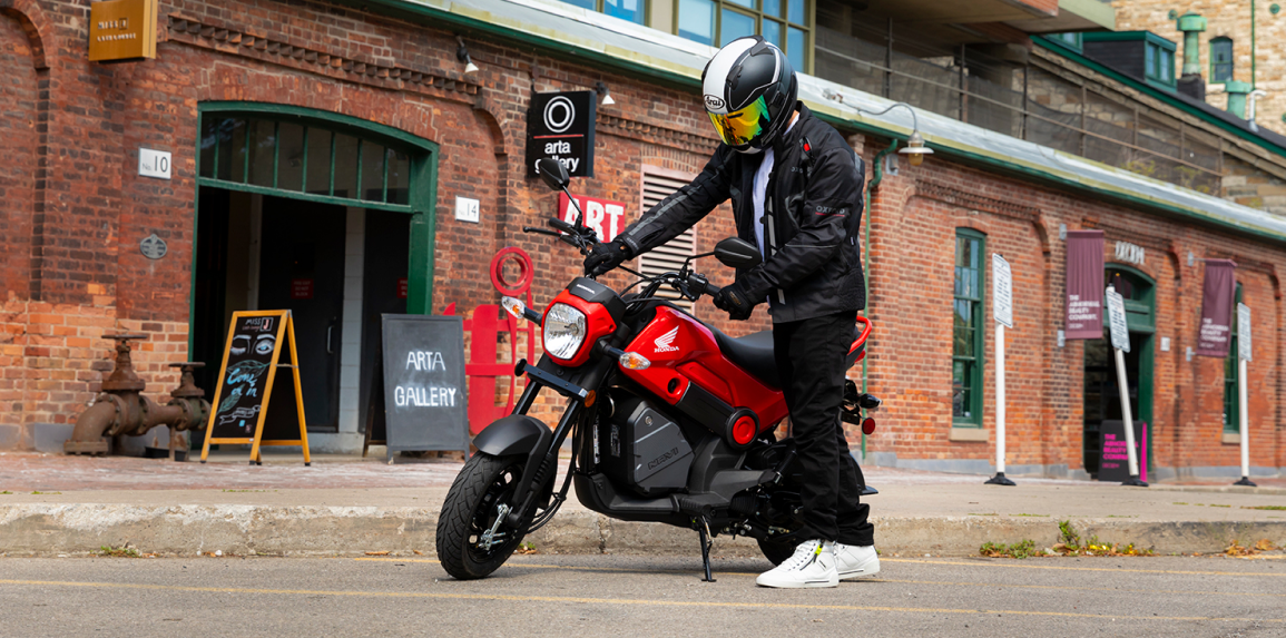 A parked Honda Navi outside of an urban building