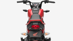 A 3/4 view of a Honda Navi and rider showing its  seat and foot pegs